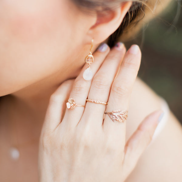 Close up jewelry lifestyle photo with 3 botanical gold rings on a white woman's hand. Organic delicate jewelry by jewelry artist Alison Jefferies for J'Adorn Designs.
