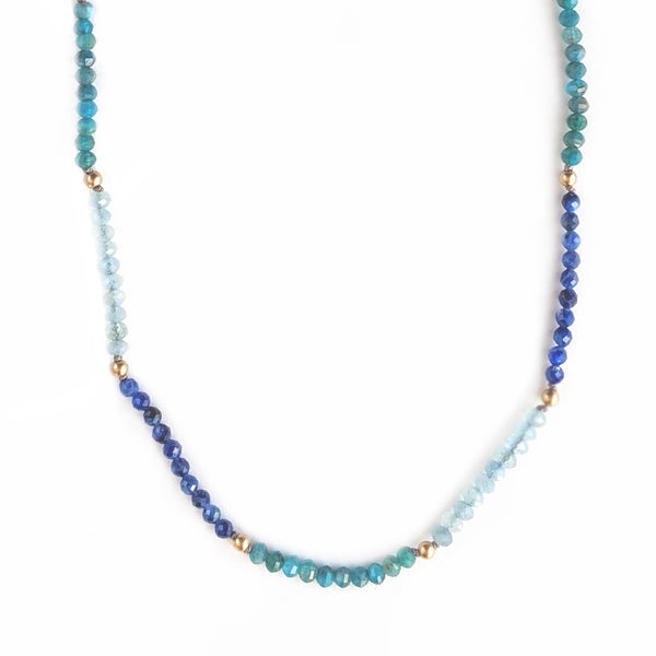 Blue ombre beaded gemstone necklace with tiny beads of aquamarine, kyanite, and apatite. Gemstone beads strung on silk thread with gold accents beads and lobster clasp. Handcrafted jewelry by artist