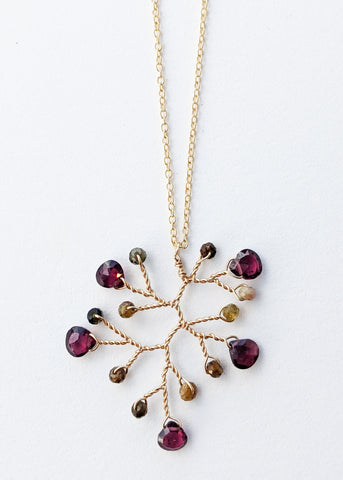 Portrait cropped image of a garnet and tourmaline wire-wrapped branch pendant necklace on a gold filled chain by Alison Jefferies for J'Adorn Designs handcrafted jewelry