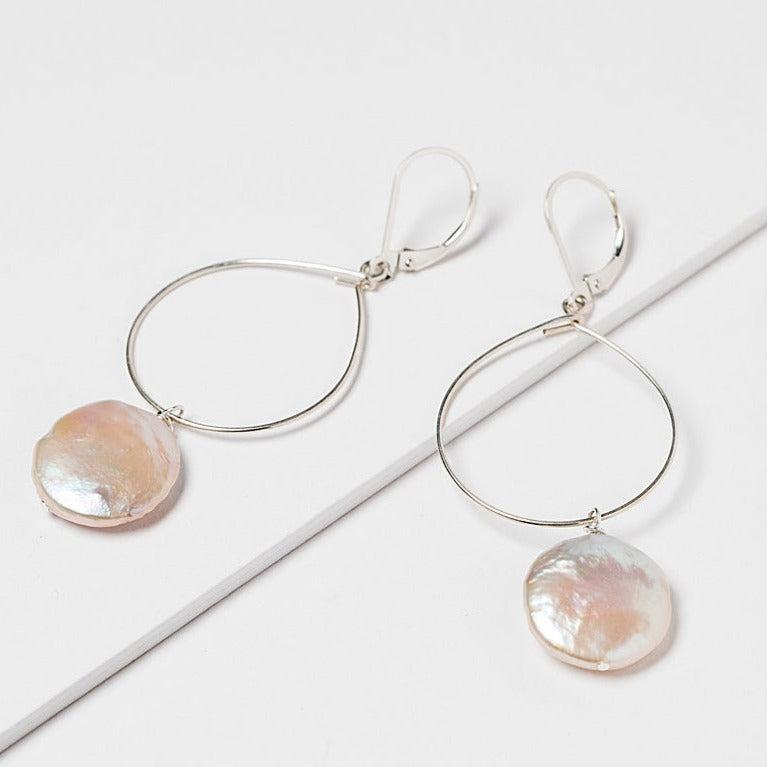 Lightweight silver hoop earrings with large pearl drops. Freshwater coin pearls on a thin silver hoop earrings. Handcrafted jewelry and modern bridal accessories by J'Adorn Designs artist Alison Jefferies.