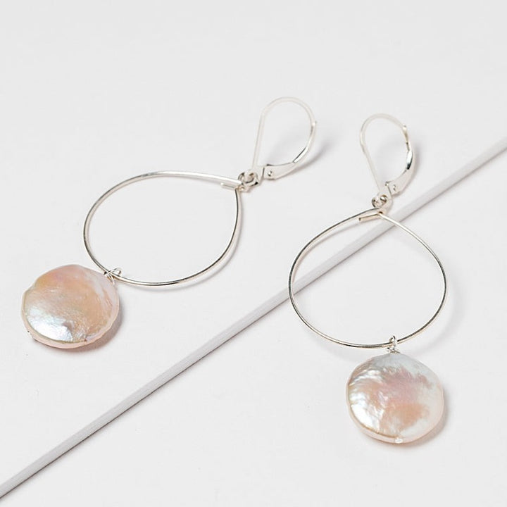 Lightweight silver hoop earrings with large pearl drops. Freshwater coin pearls on a thin silver hoop earrings. Handcrafted jewelry and modern bridal accessories by J'Adorn Designs artist Alison Jefferies.