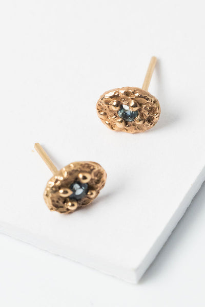 14k gold montana sapphire oval stud earrings. Textured cast gold earrings with light blue sapphires by custom jeweler Alison Jefferies for J'Adorn Desgins.