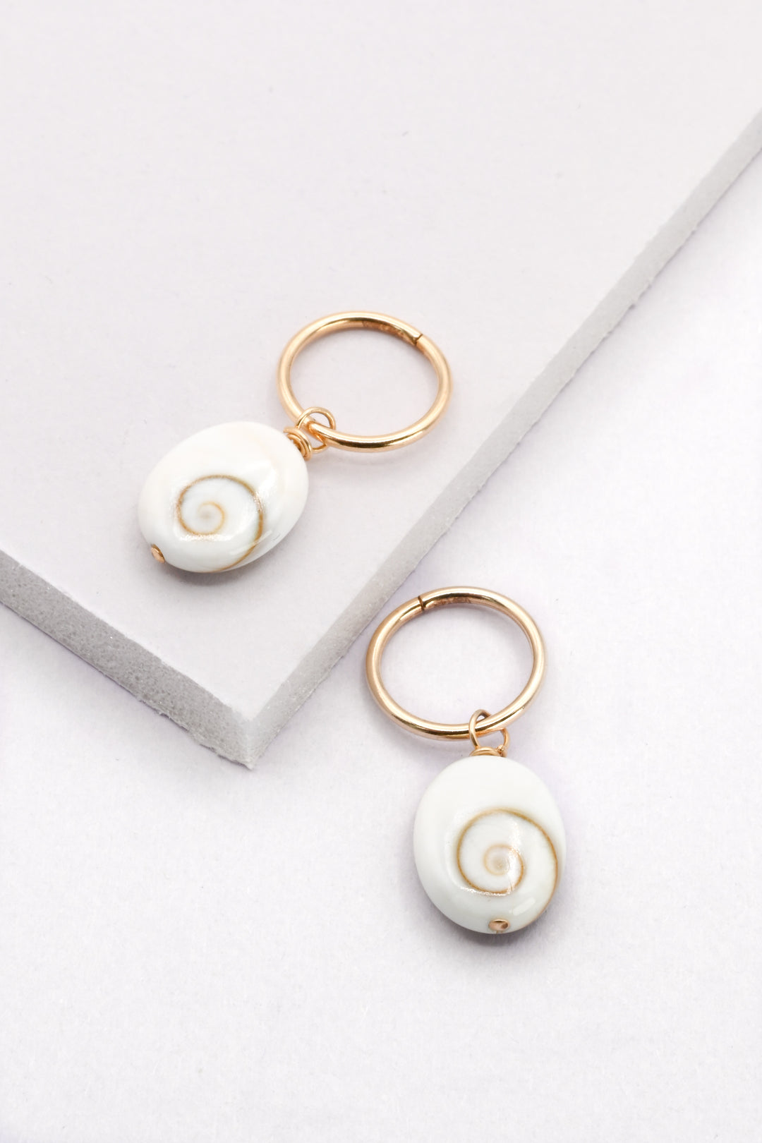 Tiny gold huggie hoop earrings with white spiral shell charms by J'Adorn Designs handcrafted jewelry. 
