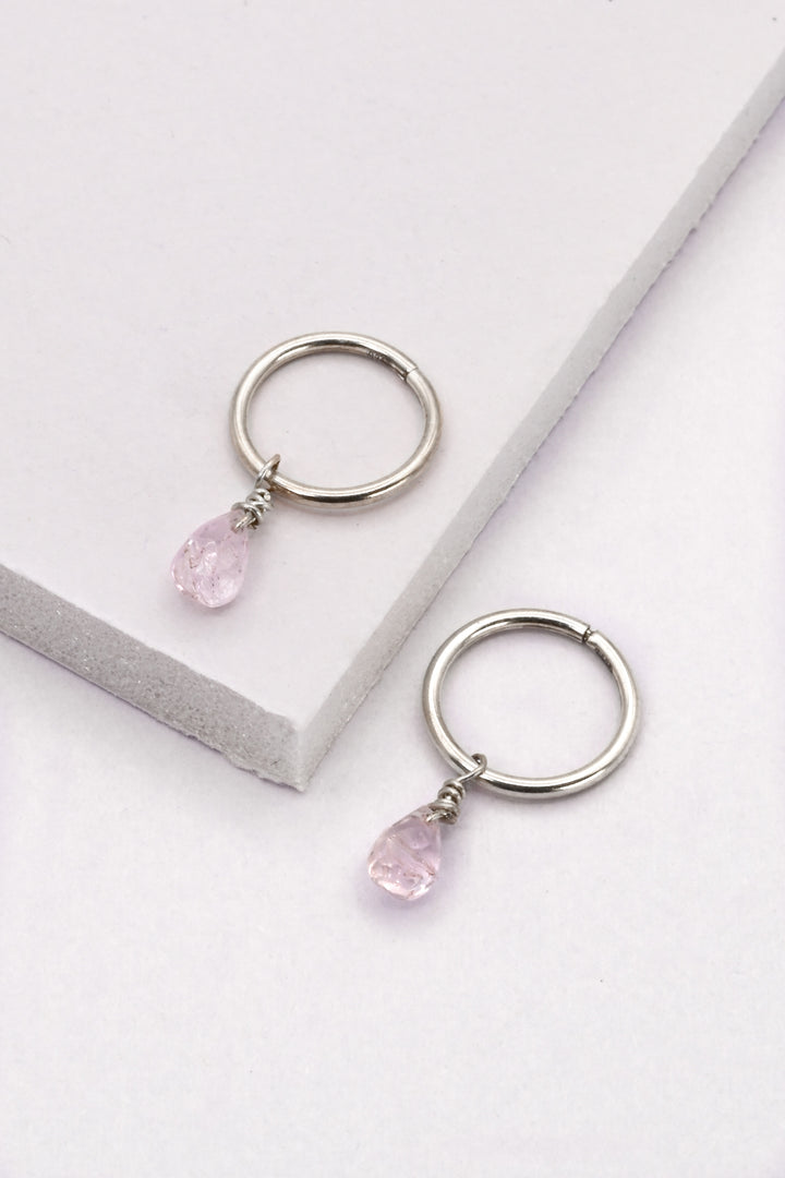 Small sterling silver seamless huggie hoop earrings with light pink sapphire charms.