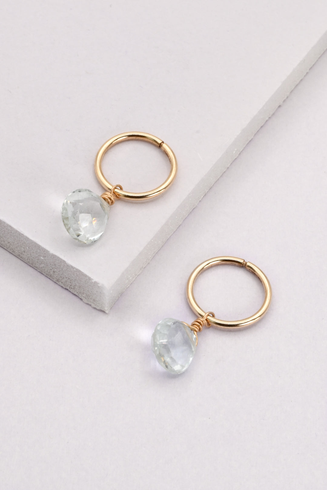 Small gold seamless huggie hoops with aquamarine teardrop charms