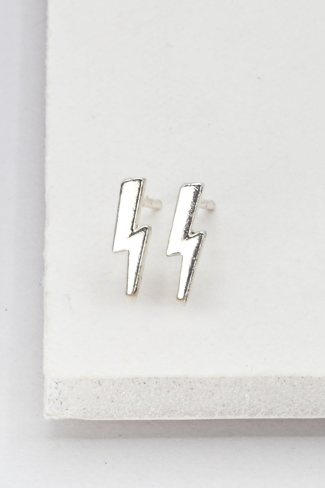 Tiny silver lightning bolt stud earrings on a white background