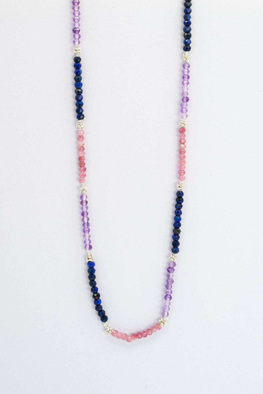 Color block beaded necklace of amethyst, sapphire, and pink tourmaline with sterling silver spacer beads and clasp.