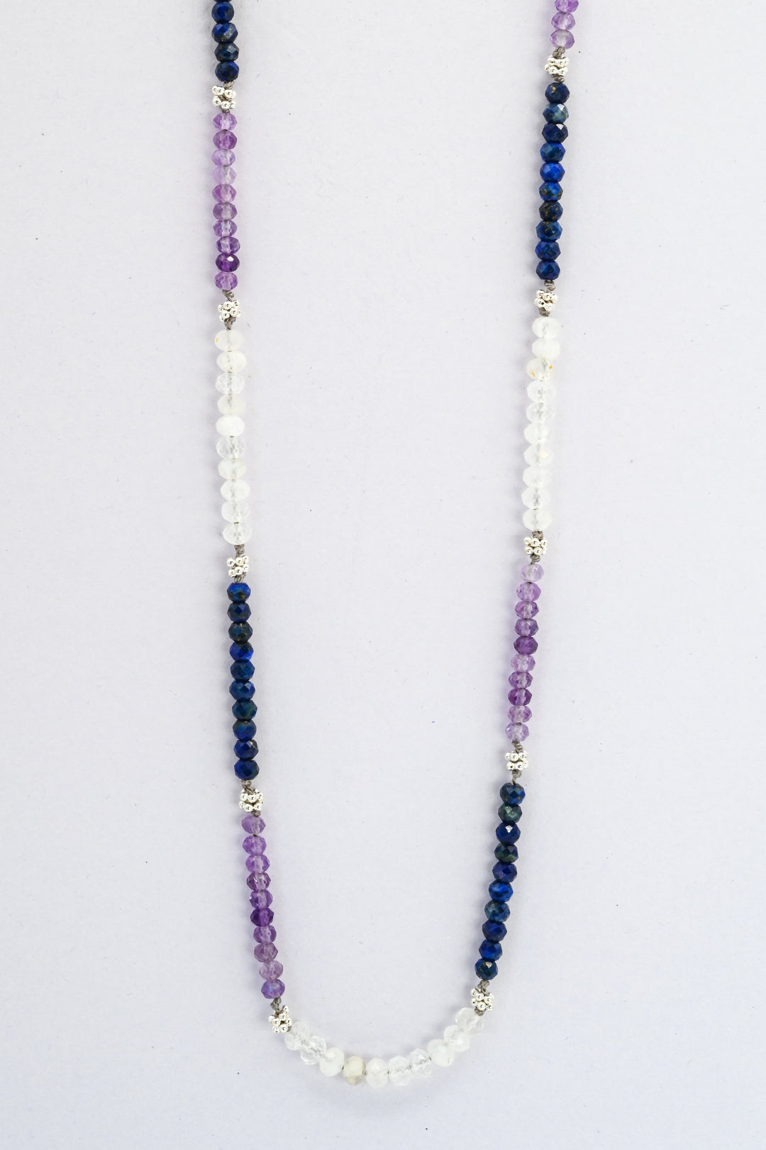 Color blocked beaded gemstone necklace with sections of amethyst, sapphire, and moonstone divided by sterling silver beads