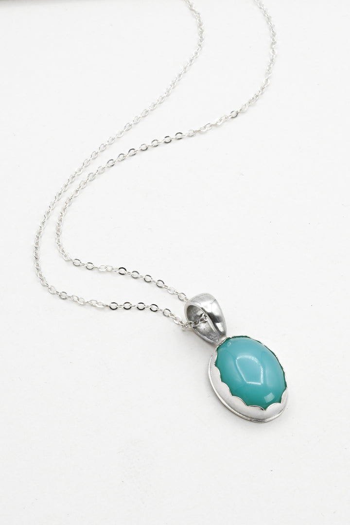 Necklace with a turquoise aquaprase pendant and delicate silver chain on a white background