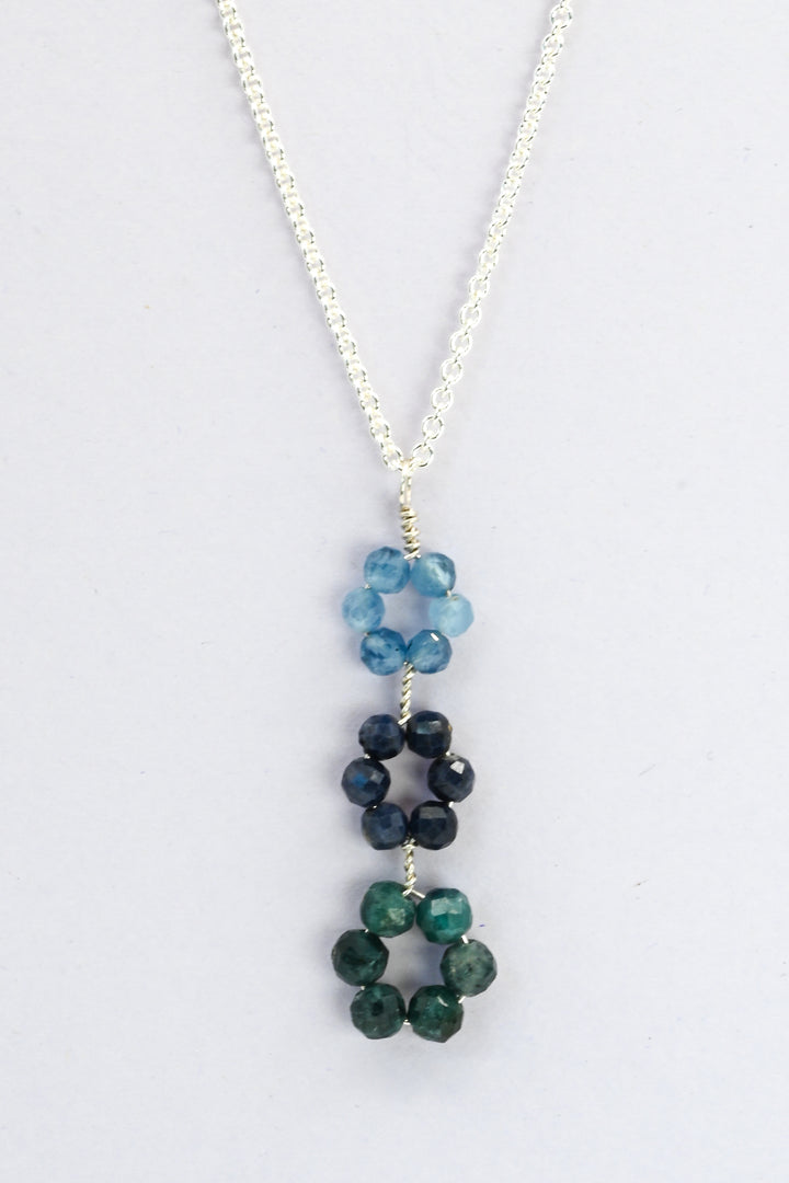 Blue triple flower pendant necklace with descending gemstone daisies in blue aquamarine, sapphire, and green tourmaline on a delicate sterling silver chain