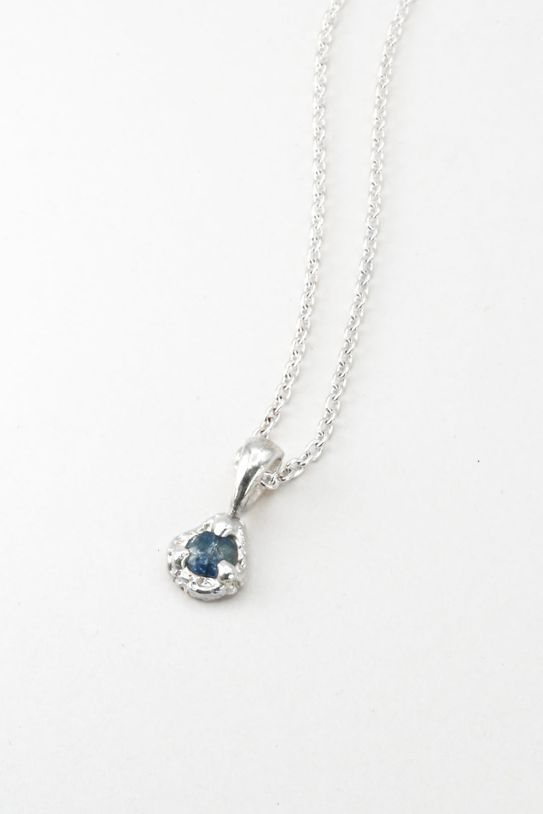 Silver necklace with a  light blue sapphire pendant on a white background