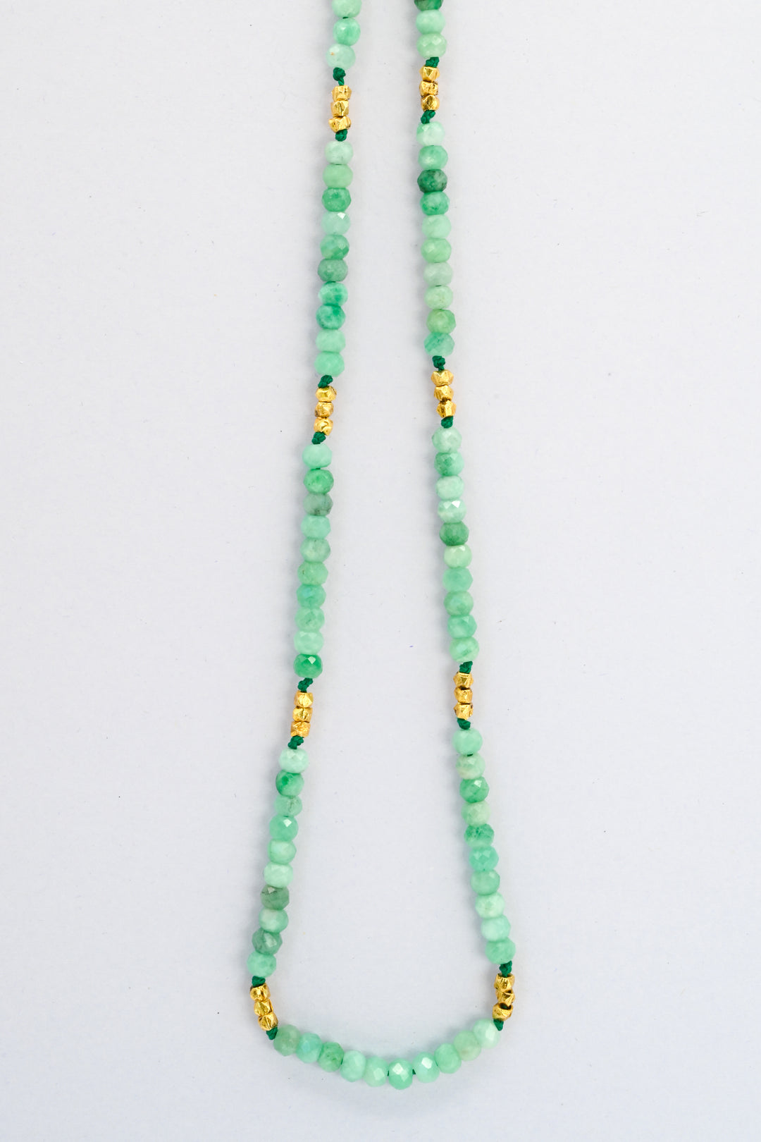 Beaded emerald necklace with faceted gold vermeil spacer beads hanging against a white background