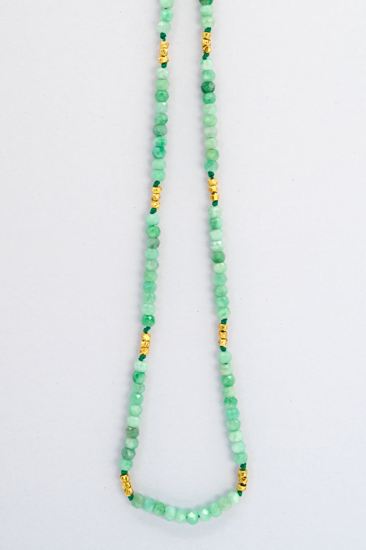 Beaded emerald necklace with faceted gold vermeil spacer beads hanging against a white background