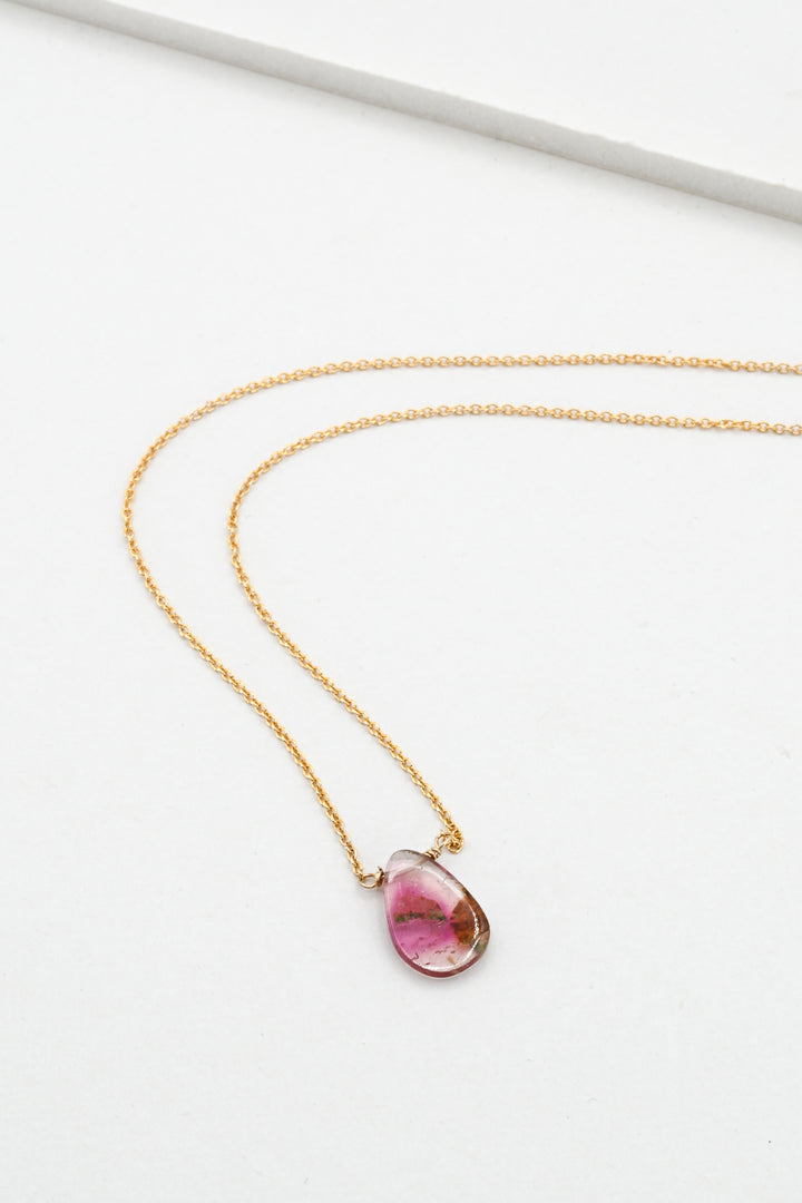Gold necklace with a teardrop-shaped watermelon tourmaline pendant on a white background