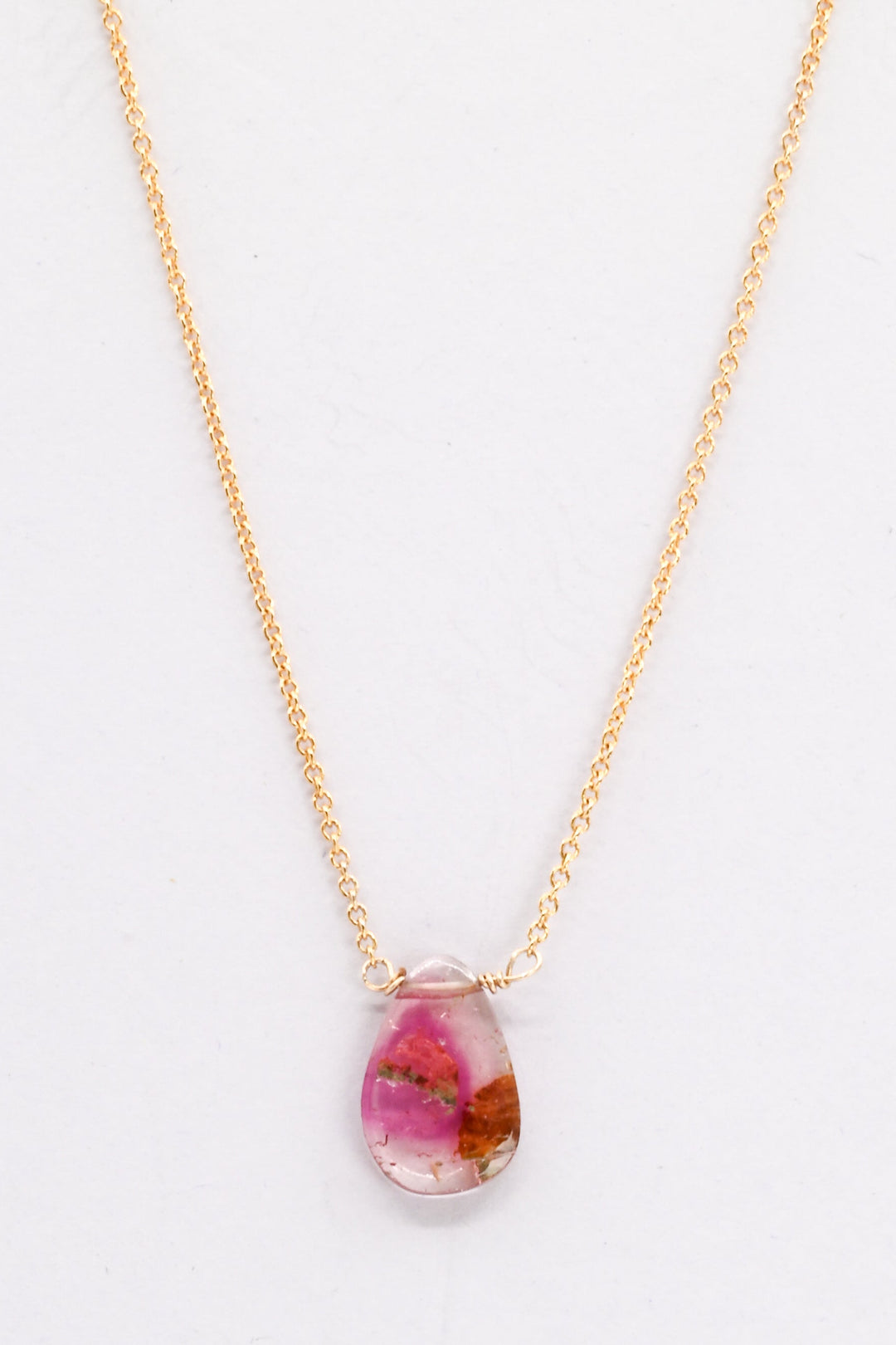Gold necklace with a teardrop-shaped watermelon tourmaline pendant on a white background