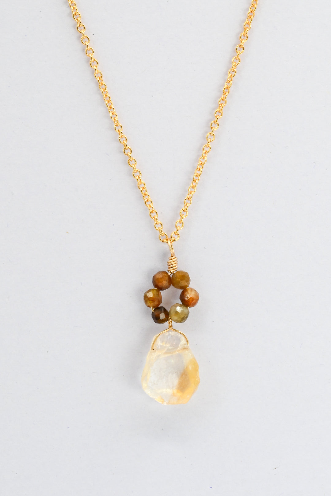 Delicate gold necklace with a pendant made of yellow citrine and small round tourmalines in a daisy flower design.