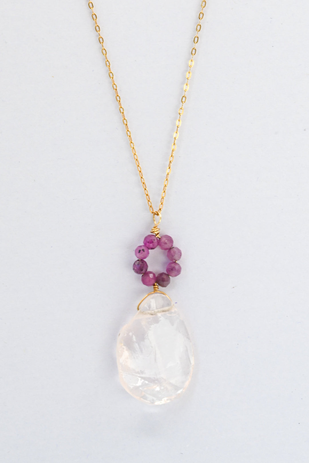 Ruby and rose quartz pendant necklace with a dark pink ruby "flower" seated above a rough translucent rose quartz teardrop, on a delicate gold chain