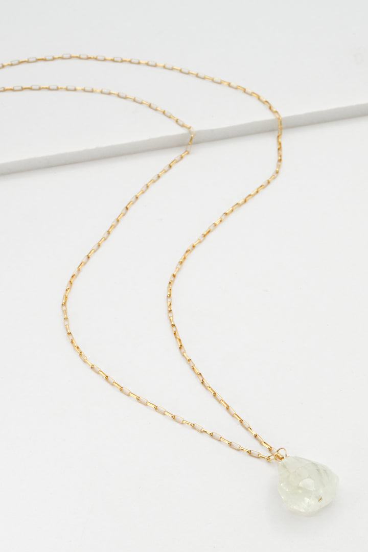 Gold necklace with a green aquamarine pendant on a white background