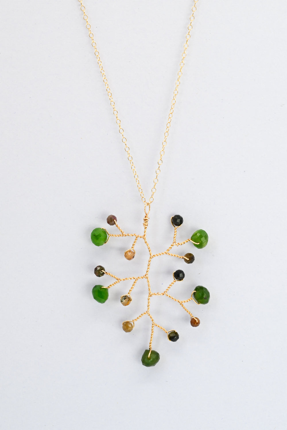 Delicate gold wire wrapped branch necklace with green jade teardrops and earthy brown and green tourmaline accent beads on a delicate gold chain