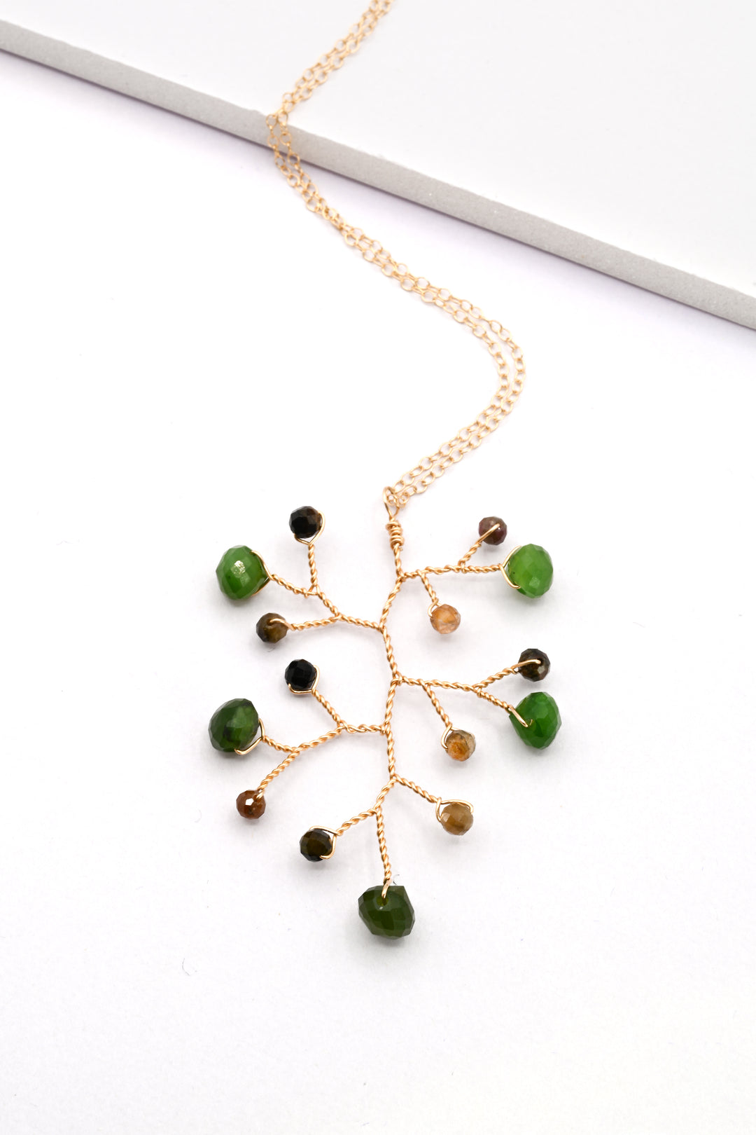 Jade and tourmaline gemstone branch necklace with a gold wire vine pendant on a matching delicate gold chain.