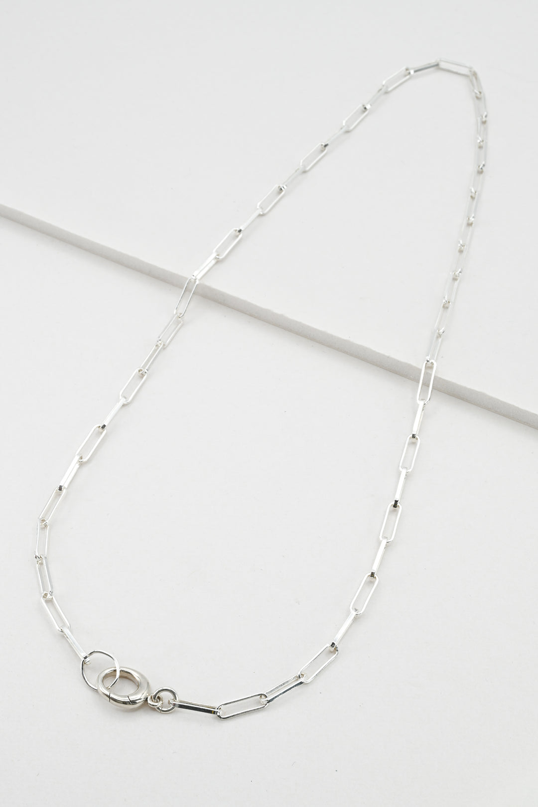 Sterling silver paperclip chain necklace with hinged charm holder clasp against a white background