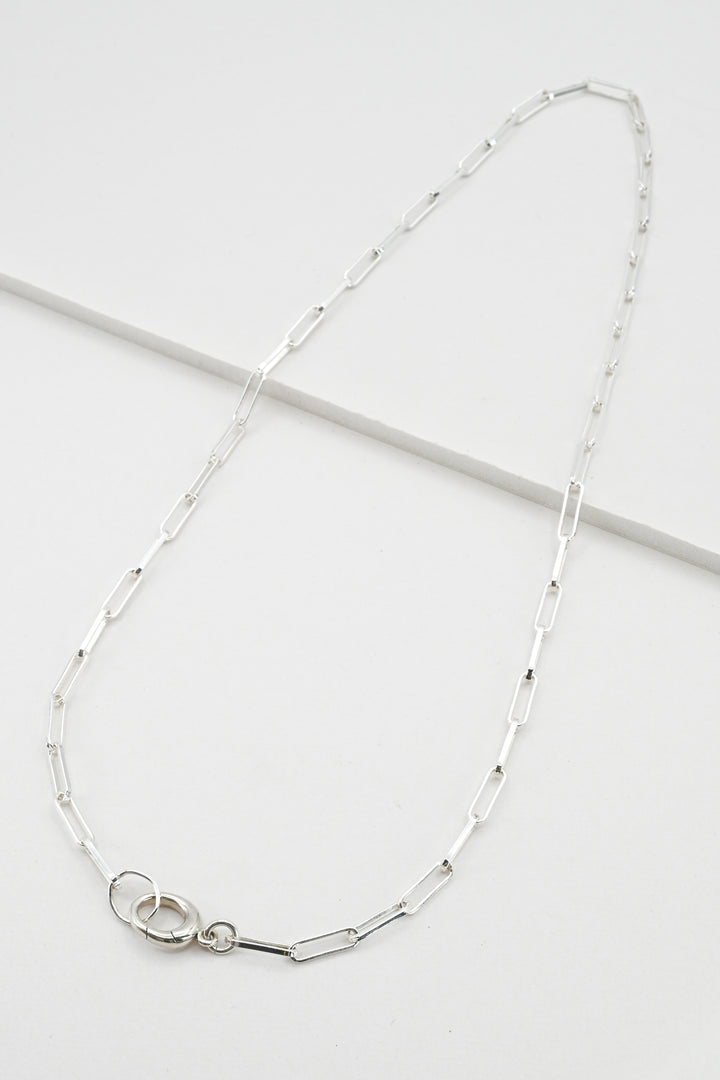 Sterling silver paperclip chain necklace with hinged charm holder clasp against a white background
