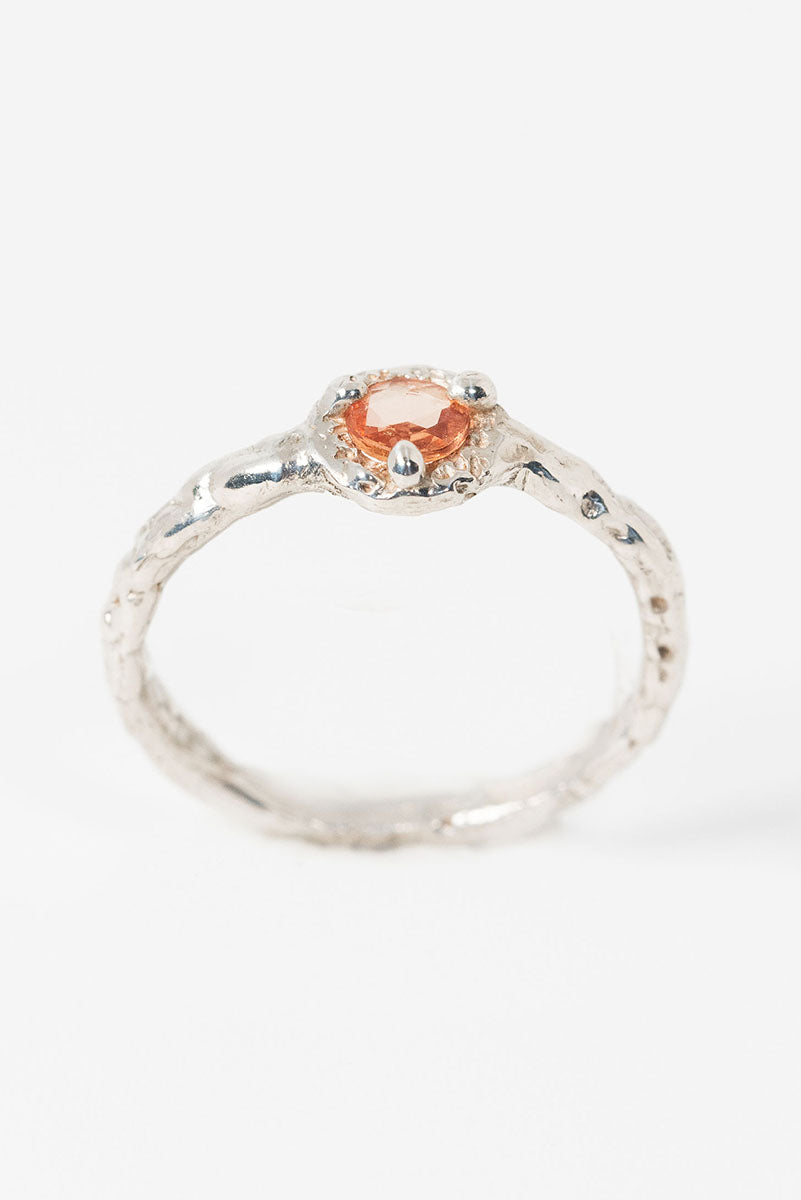 Side view of a textured silver ring with peach sapphire solitaire stone