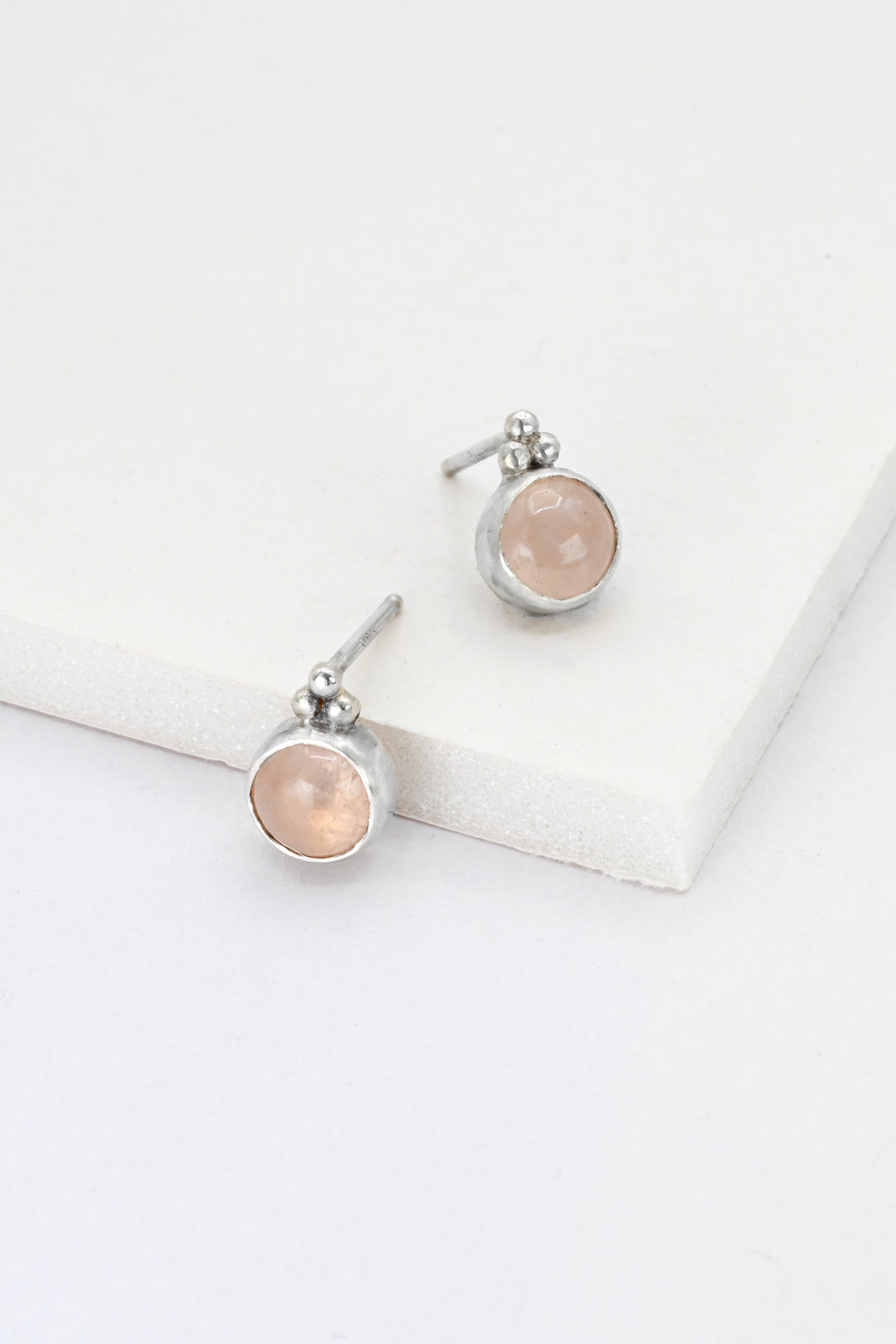 Pair of sterling silver earrings with rose quartz stones on a white surface