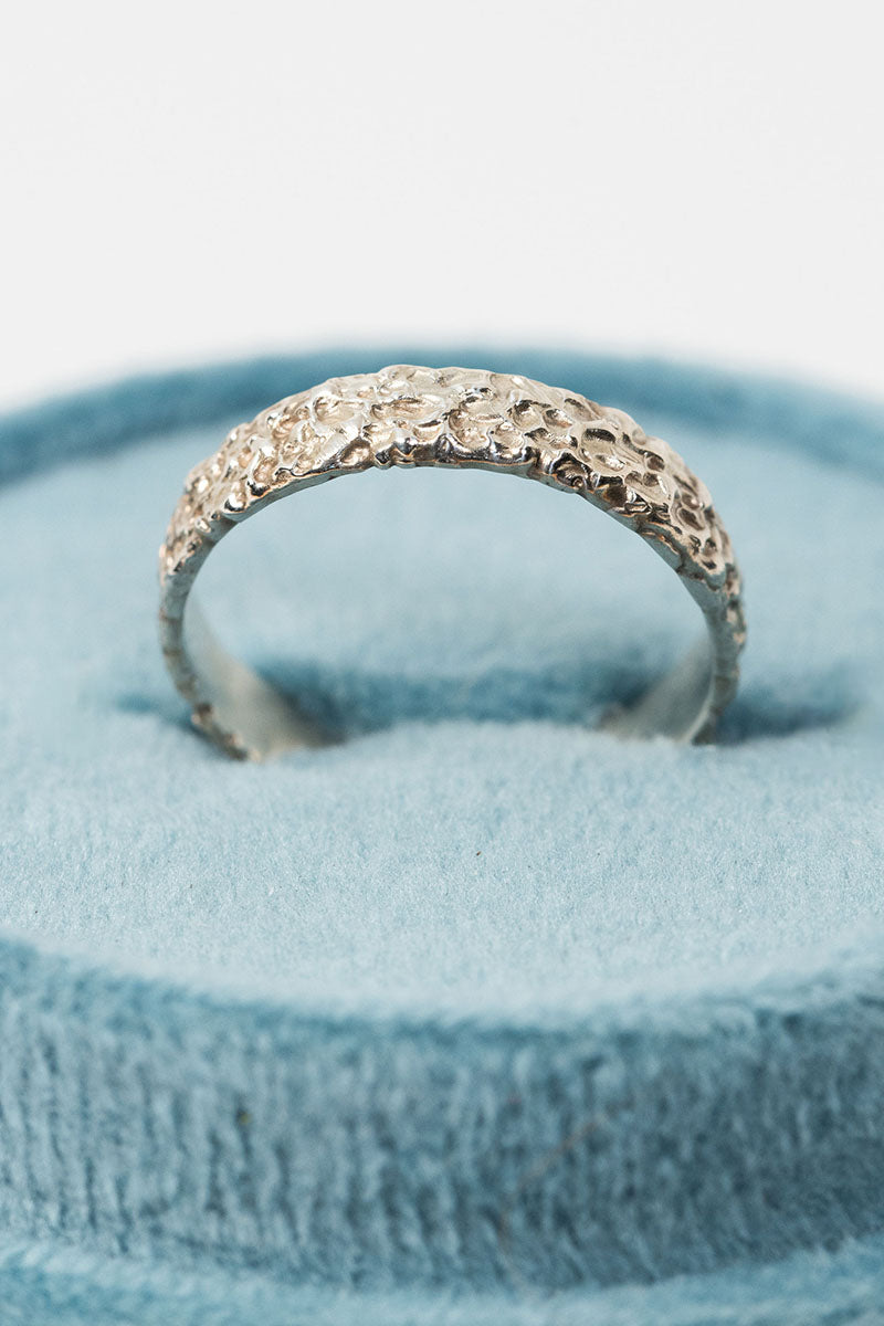 Sterling silver textured crater band stacking ring in a teal velvet ring box