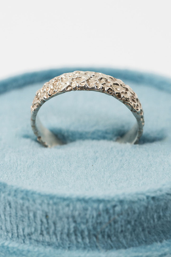 Sterling silver textured crater band stacking ring in a teal velvet ring box