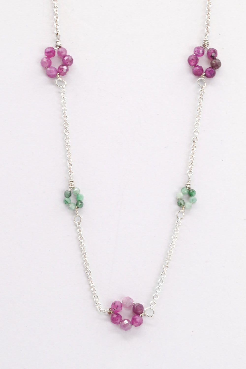 Necklace with pink ruby and green emerald bead flowers on a white background