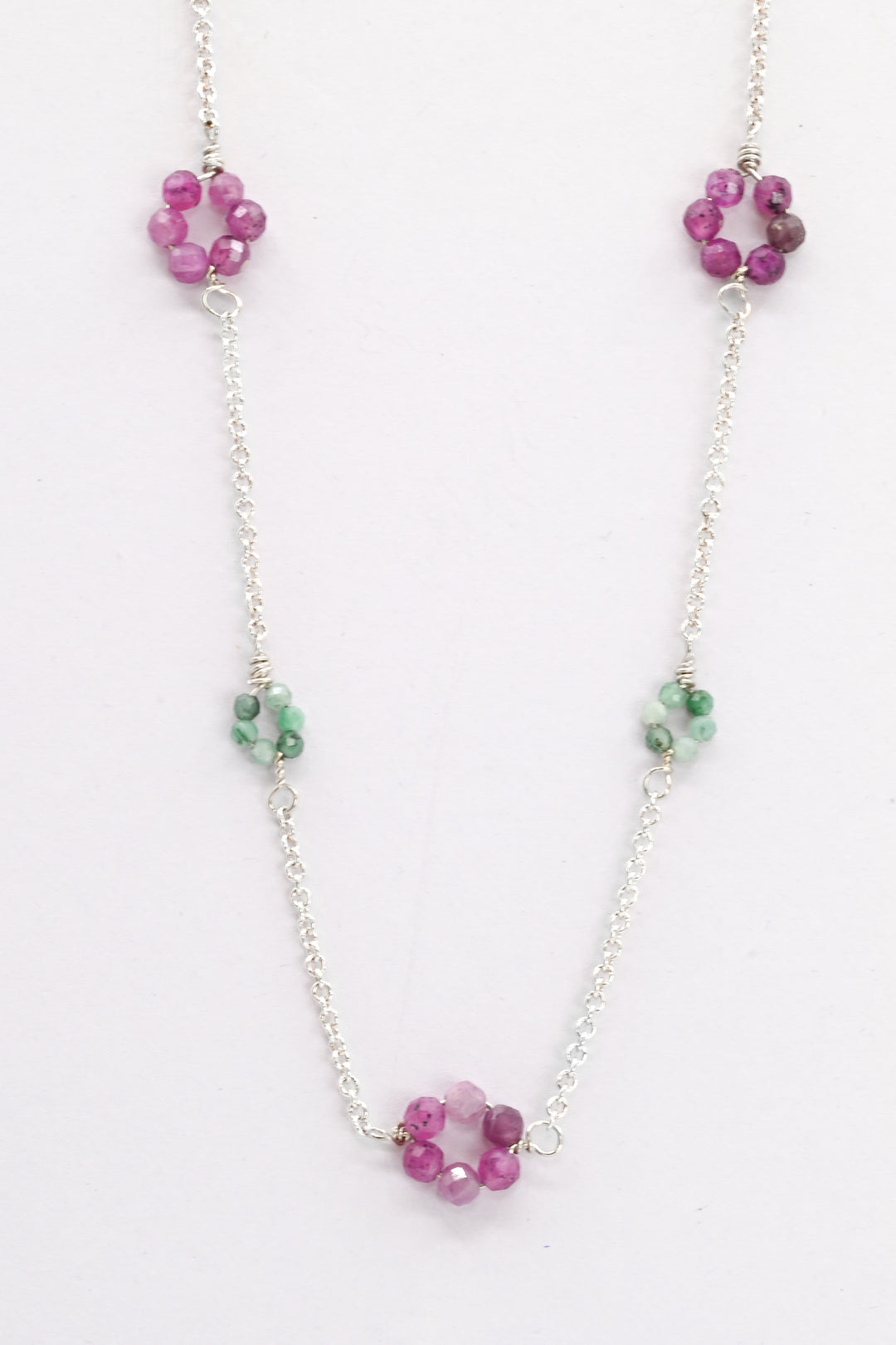 Necklace with pink ruby and green emerald bead flowers on a white background