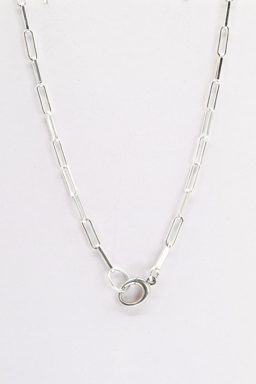 Sterling silver paperclip chain with charm holder clasp on a white background
