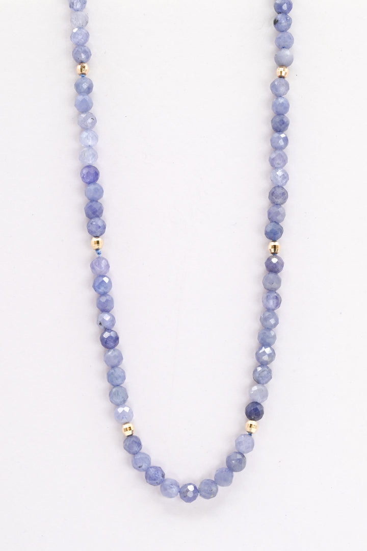 Purple tanzanite and 14k yellow gold beaded necklace against a white background 