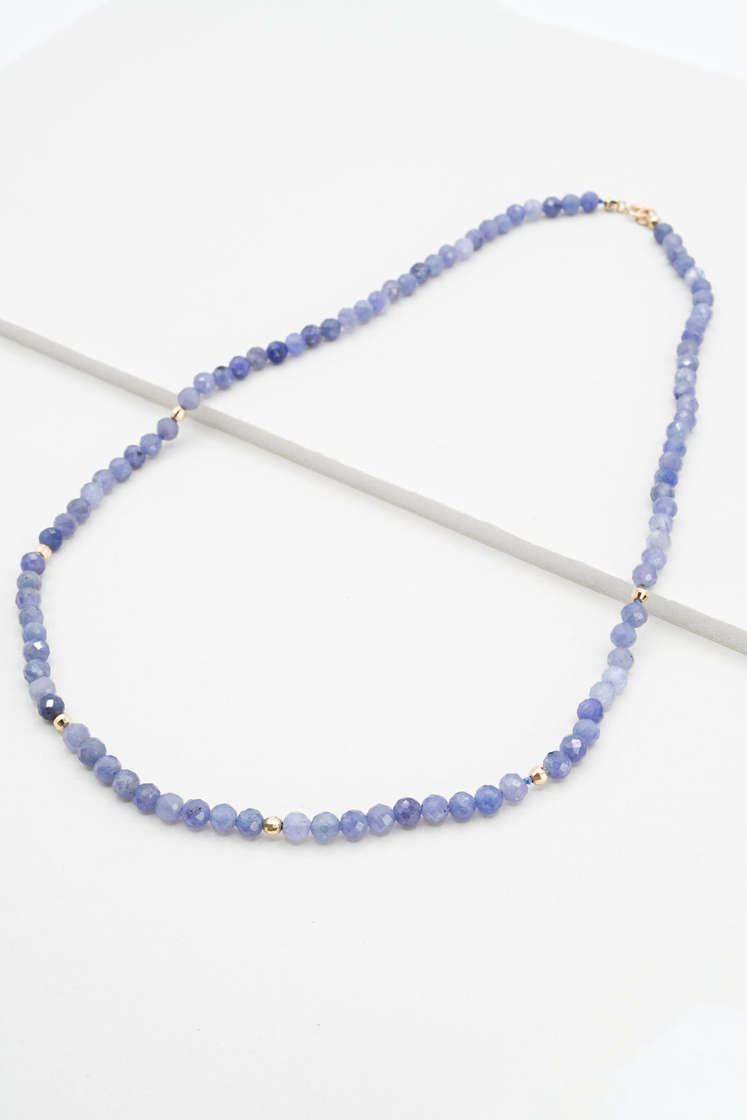 Tanzanite and 14k gold beaded necklace on a white background
