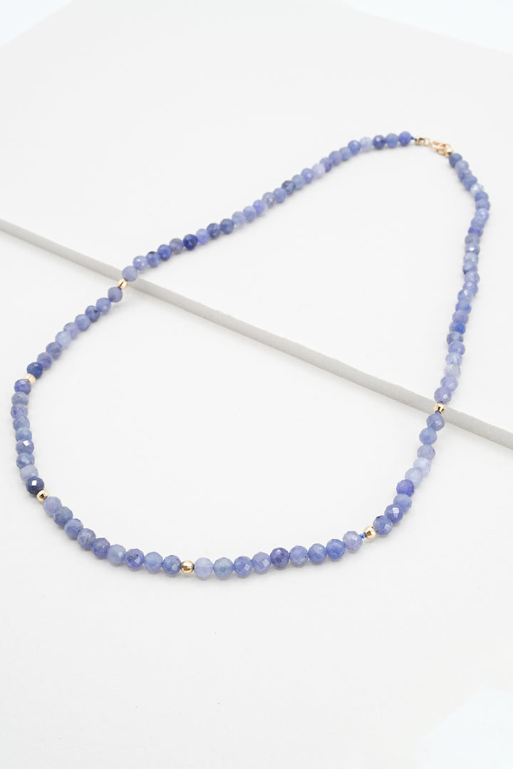 Tanzanite and 14k gold beaded necklace on a white background