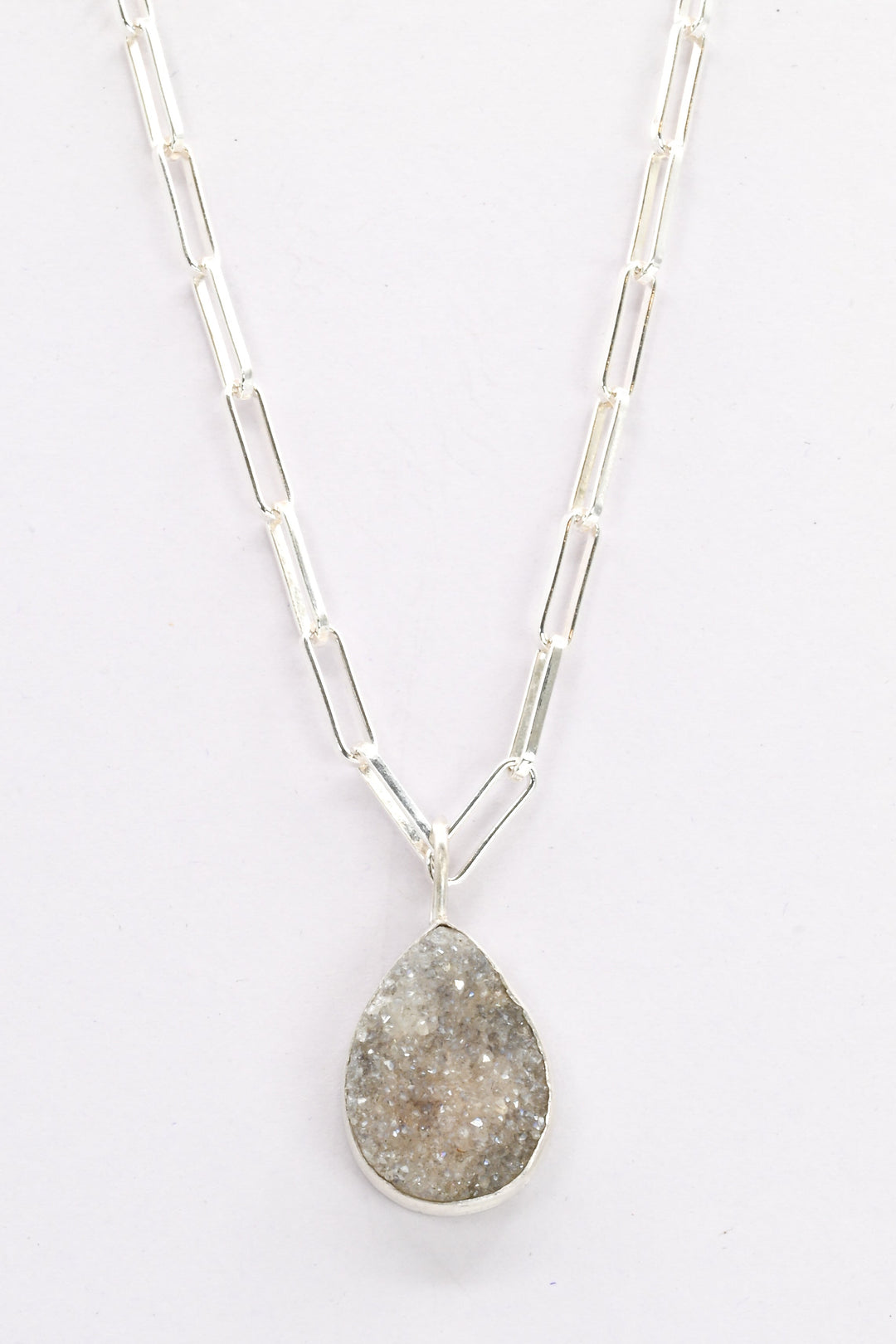 Sterling silver necklace with a purple druzy teardrop-shaped pendant on a white background