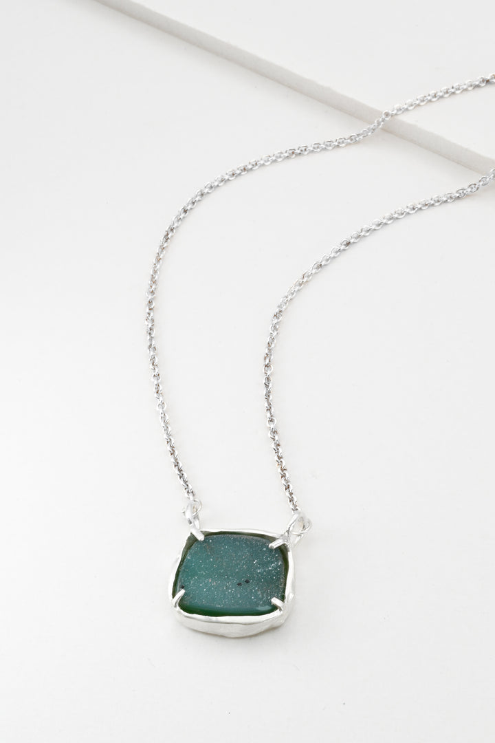 Sterling silver necklace with a green rectangular druzy pendant on a white background