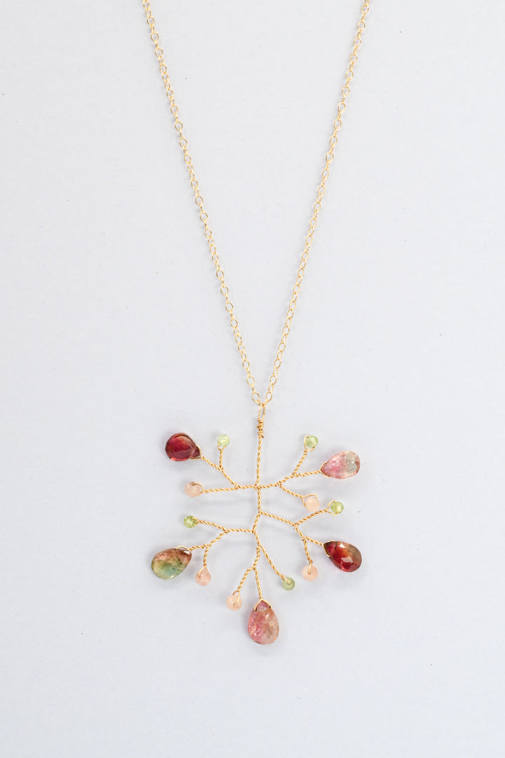Delicate vine pendant necklace with watermelon tourmaline teardrops and accent beads in green peridot and peach moonstone, on a delicate gold chain against a white background