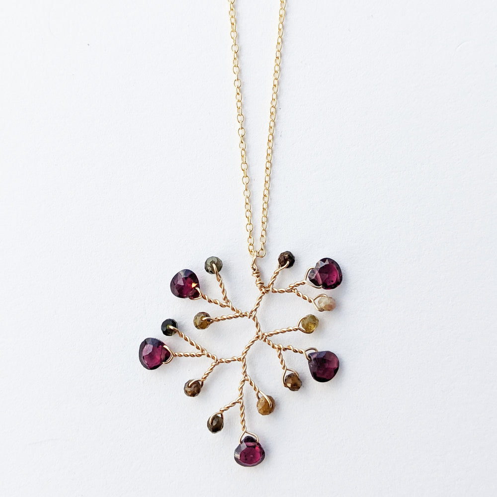 Square cropped image of a garnet and tourmaline wire-wrapped branch pendant necklace on a gold filled chain by Alison Jefferies for J'Adorn Designs handcrafted jewelry