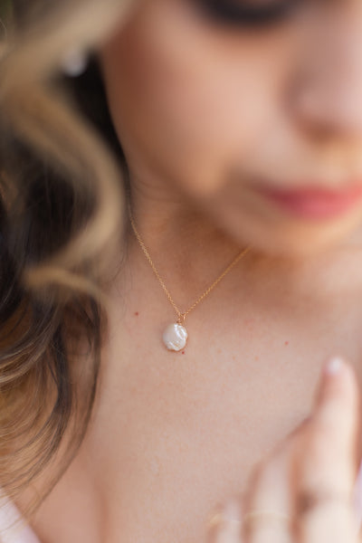 Modeled photo of a delicate freshwater pearl pendant necklace in gold. One white freshwater coin pearl on a fine golden chain by J'Adorn Designs jewelry designer Alison Jefferies