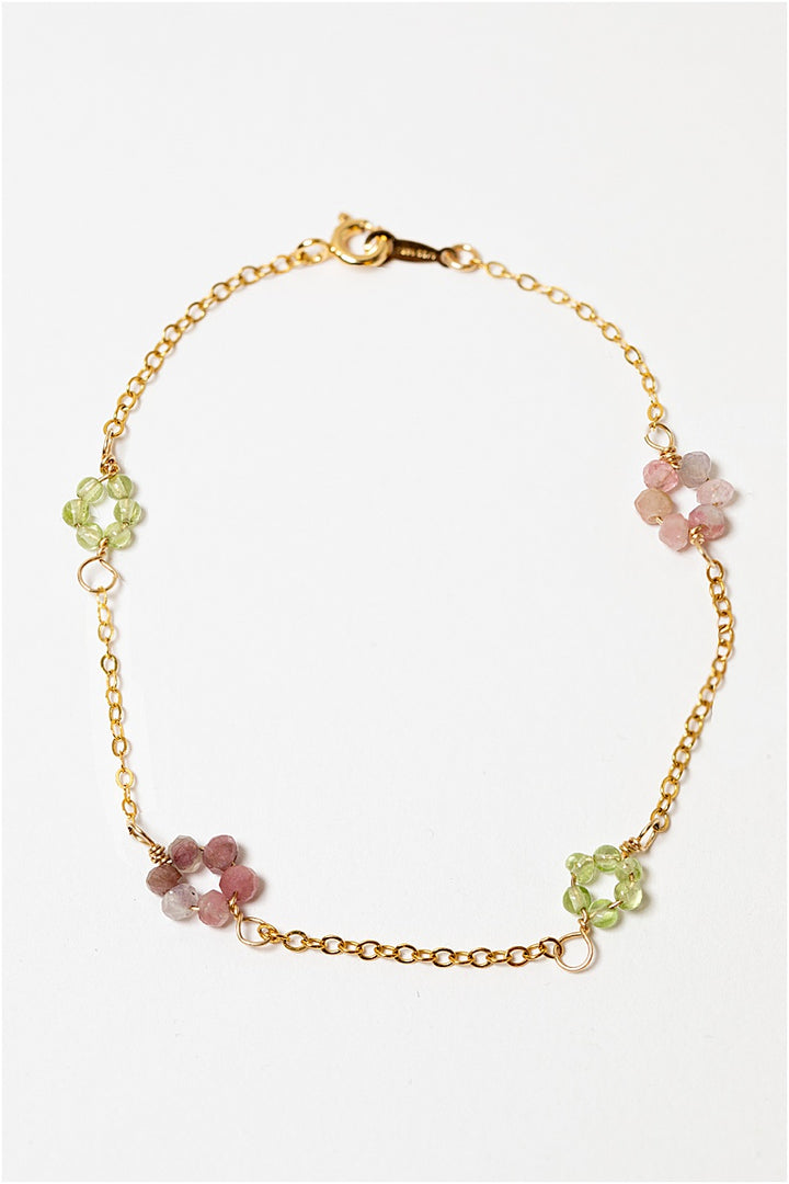 Gold daisy chain bracelet with green peridot and pink tourmaline gemstone "flowers" on a delicate golden chain. Handcrafted jewelry and custom bridal accessories by J'Adorn Designs artist Alison Jefferies.