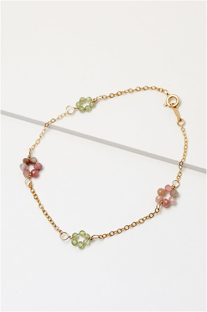 Gold daisy chain bracelet with green peridot and pink tourmaline gemstone "flowers" on a delicate golden chain. Handcrafted jewelry and custom bridal accessories by J'Adorn Designs artist Alison Jefferies.