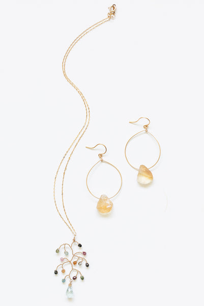 A gold handcrafted jewelry set for sale. One pair of gold hoop earrings with rough citrine teardrops, paired with a delicate tourmaline and aquamarine necklace with an abstract tree pendant. A modern earrings and necklace set for luxury fashion or a jewelry gift idea. Artisan jewelry and luxury bridal accessories handmade in Maryland by Alison Jefferies of J'Adorn Designs.