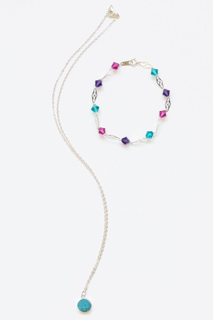 Delicate silver link bracelet for stacking or wedding jewelry. Jewel tone Swarovski crystals in pink, purple, and turquoise with silver filigree links, styled with a blue druzy pendant necklace with silver bezel setting. Mermaid colors silver bracelet. Artisan jewelry and luxury bridal accessories handmade in Maryland by Alison Jefferies of J'Adorn Designs.