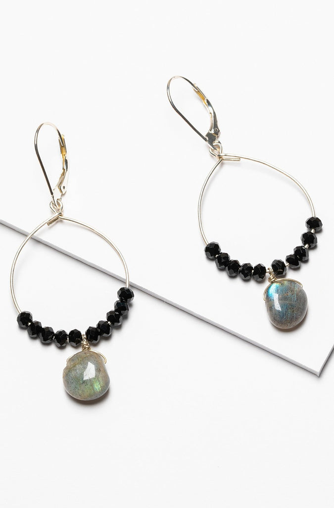 A pair of black and silver hoop earrings with black spinel and iridescent grey labradorite drops. Celestial inspired jewelry for luxury fashion or a jewelry gift idea. Artisan jewelry and luxury bridal accessories handmade in Maryland by Alison Jefferies of J'Adorn Designs.